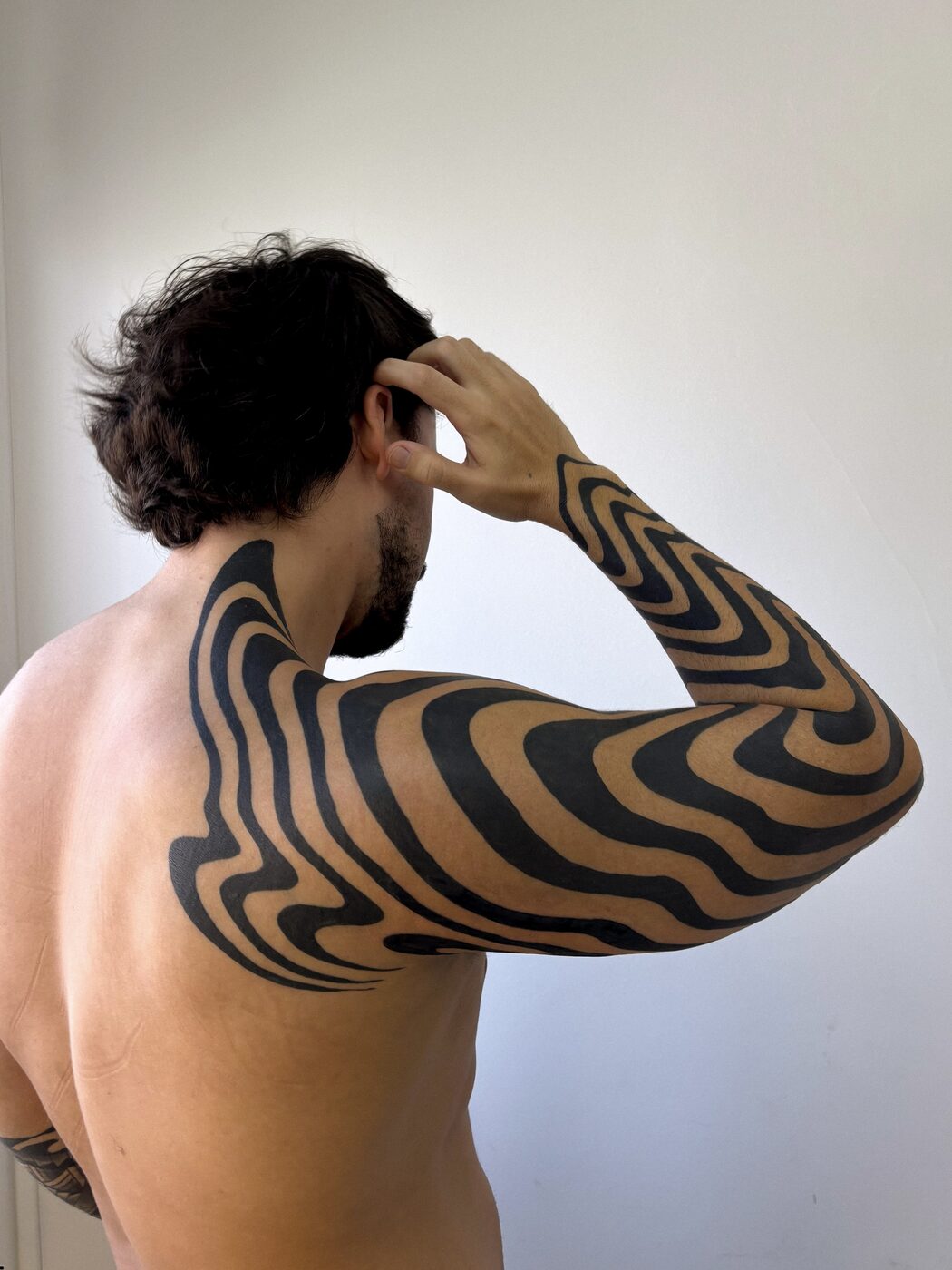 Tatuagem blackwork em costas e braço — efeito ondulado